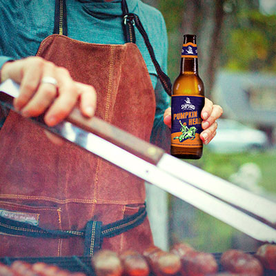 Pumpkinhead Ale bottle being enjoyed at a tailgate party with a grill